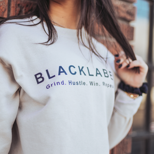 Model Light gray Blacklabel crewneck sweatshirt with “Grind. Hustle. Win. Repeat.” text.