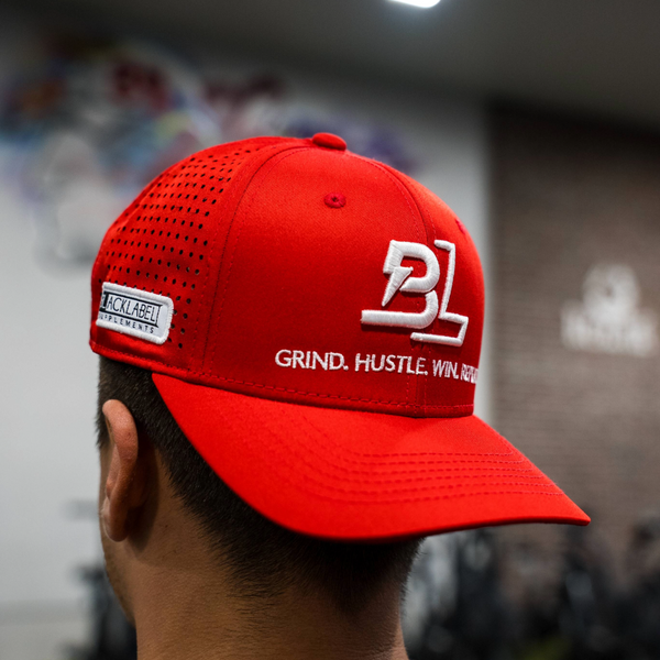 Red cap with branding and text worn by a person, blurred background